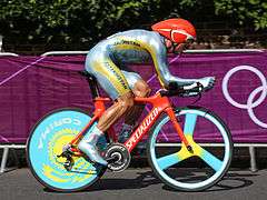 A cyclist riding a bike while wearing a skinsuit and an aerodynamic helmet.