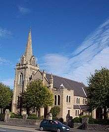 A stone building consisting of a three storey central body with pitched roof. At one corner of the building is a tower with an Octagonal spire.