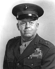 Black-and-white photo of a white man in his Marine Corps uniform. He is wearing a hat, his military awards and 2 star general rank insignia.