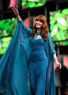 A photograph of Welch waving from a stage