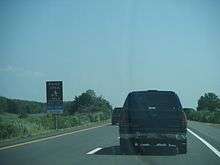 The northbound two lanes of a limited access highway with a sign on the left reading Picnic Area 1 mile keep left rest rooms closed