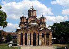 Exterior of the Gračanica monastery from the front, showing the tall and narrow central drum and dome and two of the four tall and narrow corner drums and domes of the square plan
