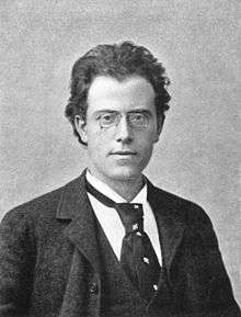 Young dark-haired man wearing a loose necktie with a white shirt and a dark jacket