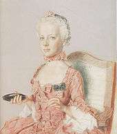  Solemn-faced girl child in a pink dress decorated with bows. Facing half-left, she carries an object in her right hand that might be a compact, or a mirror.