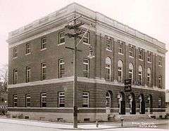 Monochrome photograph of a three-story, monumental, brick building