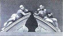 Two male figures reclining on the stone gate pillars of the Bethlem entrance, carved in Portland stone. Both figures are semi-naked. The figure on the left represents melancholic madness and looks languid and lethargic. The figure on the right, representing frenzied madness is restrained by chains and its body looks taut and muscular.
