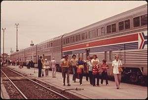 Row of silver double-deck coaches with red-white-blue striping in the middle