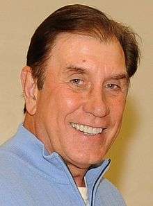 A man, wearing a light blue sweater, is looking to the front.
