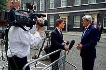 Cameraman filming journalist and a gray-haired man on the street