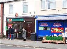 Typical street scene of the area, showing Post Office and Mini Market advertising halal meat