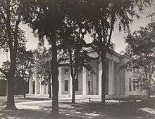 Building with columns behind trees.