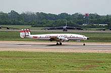 A large piston engined airliner taxying past some large bomber aircraft