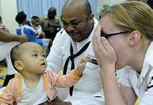 US Navy 100406-N-7478G-346 Operations Specialist 2nd Class Reginald Harlmon and Electronics Technician 3rd Class Maura Schulze play peek-a-boo with a child in the Children's Ward at Hospital Likas