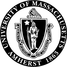 The seal of the University of Massachusetts Amherst, consisting of an American Indian holding a bow at his side in his right hand and an arrow in his left, with a five-pointed star above his right shoulder, enclosed in a shield. Around the bottom of the shield is a ribbon which reads "Ense Petit Placidam sub Libertate Quietem". Around the shield and the ribbon is a circle enscribed "University of Massachusetts / Amherst 1863". The entire seal is in black and white.